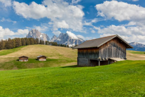 Alpe di Siusi - Seiser Alm, Characteristic mountain barns with Sassolungo / Langkofel and the Sassopiatto / Plattkofel in the background, Dolomites, Kastelruth, South Tyrol, Italy Alpe di Siusi - Seiser Alm, Characteristic mountain barns with Sassolungo / Langkofel and the Sassopiatto / Plattkofel in the background, Dolomites, Kastelruth, South Tyrol, Italy